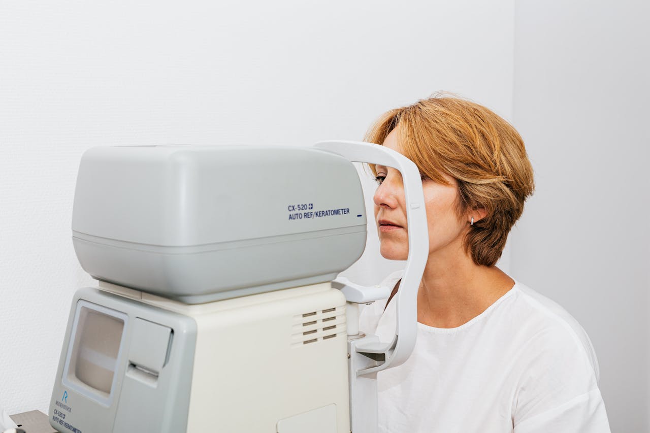 A woman undergoes an eye examination using an autorefractor machine in a clinic.