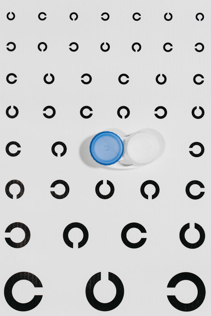 Contact lens case on an eye test chart with circular symbols for ophthalmology testing.